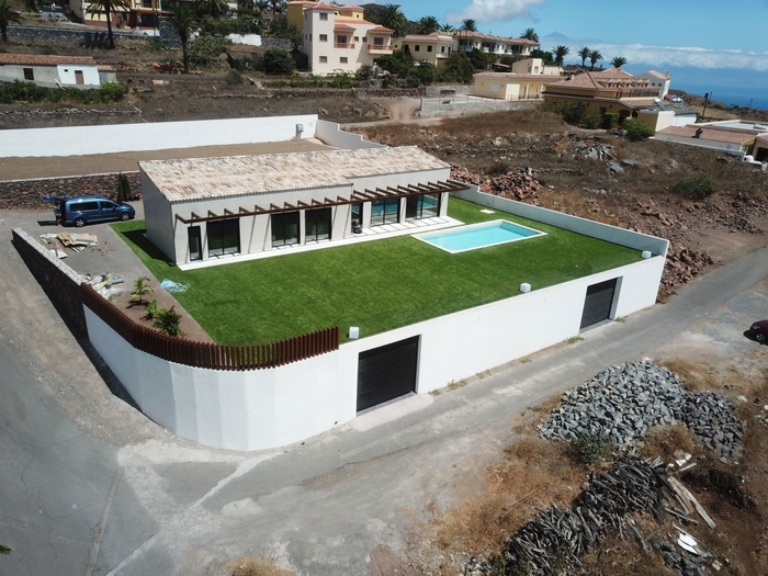 Vista desde arriba de casa modular de una planta con terreno ajardinado y piscina